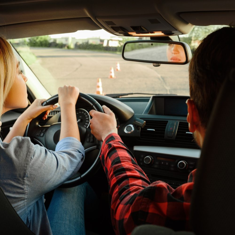 Instructor helps woman to drive the car